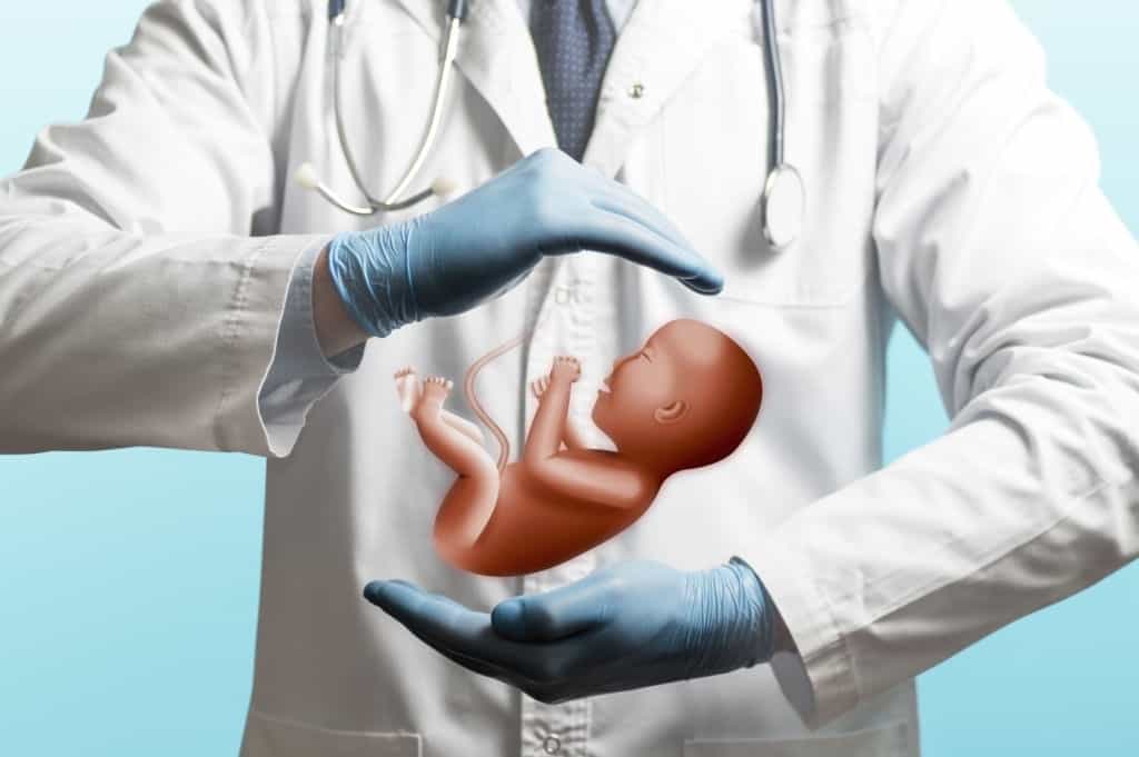 image of a doctor in a white coat and baby above his hands. care of the infant.