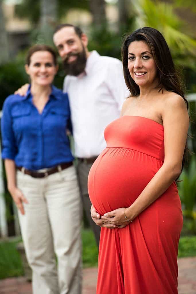 pregnant hispanic surrogate mother posing with the babies future parents