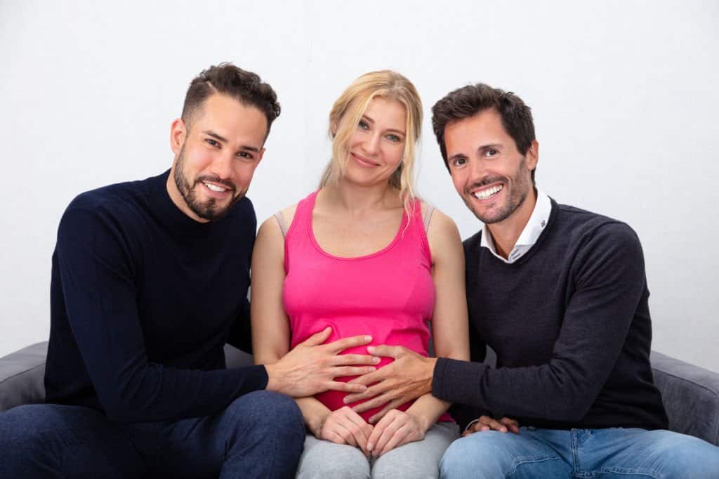 portrait of a smiling men touching the belly of pregnant surrogate woman